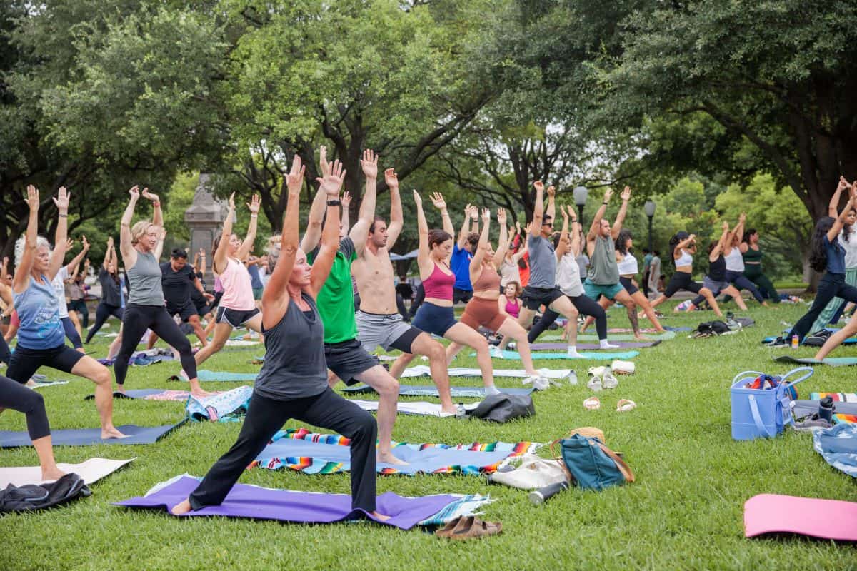 Group of people practicing yoga outdoors in a park at The Bell District.